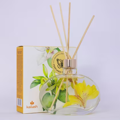 Difusor de ambiente Kailash em frasco de vidro transparente com flores amarelas e verdes, acompanhado de caixa de papelão com logotipo e informações do produto.