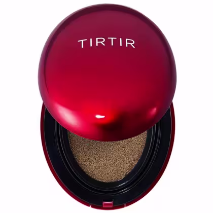 Trata-se de um produto de maquiagem da marca Tirtir, em uma embalagem redonda de cor vermelha com o nome da marca em destaque. O produto parece ser um tipo de base ou corretivo, com uma textura granulada em tom dourado visível em seu interior.