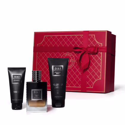 A imagem um frasco de eau de parfum, um gel de banho e uma loção para o corpo masculina O.U.i. Os itens estão na frente de uma caixa retangular vermelha decorada com padrões geométricos em cor creme e laço vermelho.