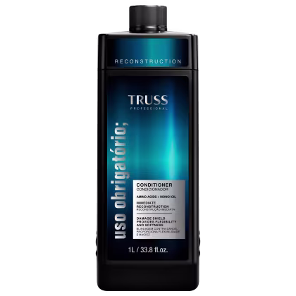 A imagem mostra um frasco de condicionador com uma tonalidade preta e rótulo com fundo azul escura. Traz informações na cor cinza e preta. O tamanho do frasco é de 1l ou 33,8 fl.oz.