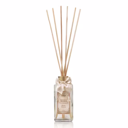 Difusor de aromas em frasco de vidro transparente com tampa dourada e laço de cetim bege. Rótulo com texto "Difusor de Aromas" e "Frutas Frescas". Hastes de madeira inseridas no frasco para dispersão do aroma.