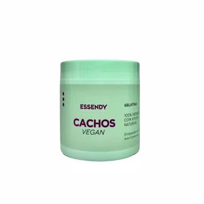 O produto apresentado é um pote de gelatina Essendy Cachos Vegan. A embalagem é verde clara, com o nome da marca "Essendy" e o produto "Cachos Vegan" escrito em roxo. O recipiente possui um formato cilíndrico e uma tampa.