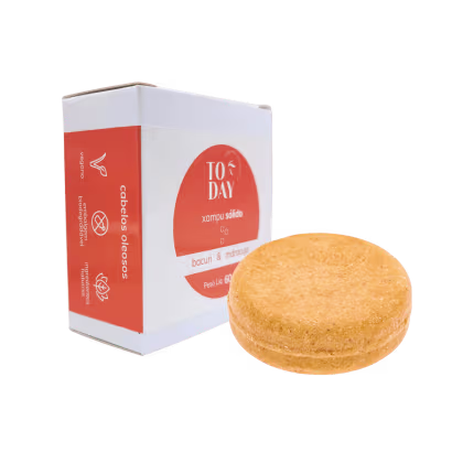 O produto apresentado é o shampoo sólido Bacuri & Maracujá da marca Today Natural Cosmetics. Ele vem em uma caixa branca com detalhes em laranja. Ao lado, há uma barra sólida de cor laranja com uma textura ligeiramente granulada.