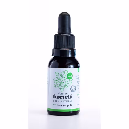 O produto apresentado é um óleo de hortela 100% natural da marca Tom de Pele. O frasco é de vidro escuro com um conta-gotas preto na tampa. O rótulo possui uma ilustração de folhas de hortela e informações sobre o produto, como o volume de 30 ml.