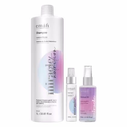 O conjunto de produtos Emáh Hair Care inclui um frasco de shampoo branco com rótulo rosa e azul, um frasco de máscara líquida e um frasco de óleo capilar, todos com embalagens e rótulos característicos da marca.