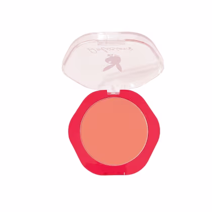 Compacto de blush em embalagem vermelha com logotipo da Playboy, contendo um tom de laranja vibrante. O produto possui uma tampa transparente que permite visualizar a cor do blush.