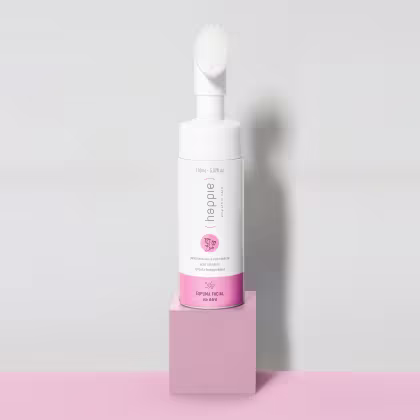 Frasco branco de espuma facial da marca Happie&Co, com rótulo rosa e informações sobre o produto. O frasco possui um aplicador de espuma na parte superior.