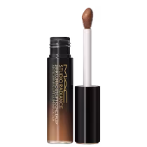 A imagem mostra um corretivo líquido que vem em um frasco degradê em tom preto e bege. Ao lado está o aplicador, que possui um formato oval com base preta. No frasco, está escrito " M·A·C Studio Radiance 24hr Luminous Lift Concealer" em um tom dourado.