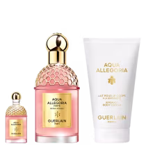 A imagem mostra um kit com perfume, versão travel size e body lotion. Os perfumes em frascos rosa com detalhes e tampas dourados, e o body lotion com embalagem branca.