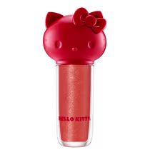Maquiagem em formato cilíndrico com a cabeça da personagem Hello Kitty como tampa. A parte superior é vermelha com detalhes em relevo que representam os olhos, orelhas e laço da Hello Kitty. É possível ver a cor do produto pelo corpo transparente.