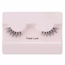 A imagem mostra os cílios postiços em um estojo plástico claro. O estojo tem uma cor nude claro e exibe um par de cílios postiços pretos.