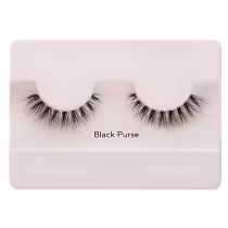 A imagem mostra os cílios postiços em um estojo plástico claro. O estojo tem uma cor nude claro e exibe um par de cílios postiços pretos.