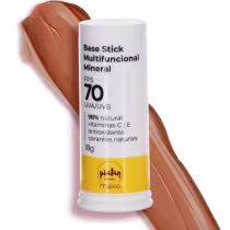 Base Stick Multifuncional Mineral da marca Piatan Natural. Embalagem cilíndrica branca com tampa plástica. Rótulo com informações como "FPS 70, UVA/UVB, 98% natural, vitaminas C e E. Ao fundo amostra da cor bege escura da base.