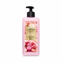 Embalagem plástica transparente de 400ml. O creme é rosa claro e o rótulo traz imagens de macarons e flores cor-de-rosa e exibe o nome do produto em um retângulo dourado ao centro. A tampa é preta, sendo um aplicador tipo bomba.