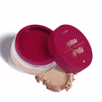 Embalagem redonda de plástico transparente com tampa protetora vermelha. Rótulo na tampa vermelha em letras douradas. Pequenas perfurações na parte interna da tampa para aplicação do pó. Pó solto espalhado ao lado exibindo a textura do produto.