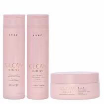 A imagem mostra três produtos de cuidados capilares da marca Braé, da linha Glow Shine. São um shampoo, um condicionador e uma máscara capilar. Os frascos do shampoo e condicionador são cilíndricos, de plástico rígido na cor rosa claro.