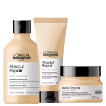 A imagem mostra um kit da linha Absolut Repair da L'Oréal Professionnel, com um frasco de shampoo, uma bisnaga de condicionador e um pote redondo de máscara, todos de cor bege com rótulo branco e tampa preta.