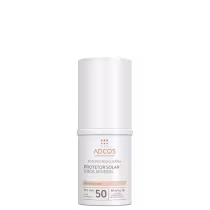 Protetor solar stick mineral Adcos, embalagem cilíndrica branca. Rótulo com texto "Fotoproteção Diária Protetor Solar Stick Mineral Translúcido FPS UVB 50 Alta Proteção FP-UVA 18". Produto de fotoproteção diária em formato stick para aplicação tópica.