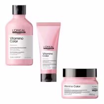 A imagem mostra uma linha de produtos para cabelos coloridos da marca L'Oréal Professionnel, da série Vitamino Color. Os produtos incluem um shampoo em um frasco plástico rosa, um condicionador em um tubo rosa e um tratamento condicionante em um pote rosa
