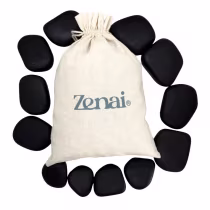 Saco de lona branco com logotipo da marca Zenai, contendo pedras pretas de massagem. O saco possui um cordão de fechamento e as pedras apresentam formato arredondado e liso.