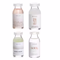 A imagem mostra quatro frascos de vidro transparente da marca Brae, contendo diferentes produtos de tratamento capilar. Os frascos têm tampas brancas e rótulos com o nome da marca e do produto.