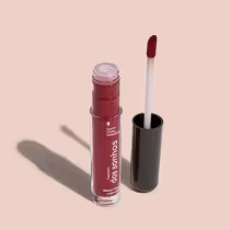 Batom líquido Marrom em frasco transparente de plástico, com aplicador de espuma na cor marrom. O frasco possui uma tampa protetora preta para guardar o aplicador. O rótulo no frasco exibe o nome da marca e do produto em letras brancas sobre fundo marrom.