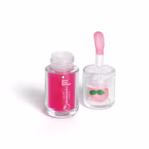 Frasco de lip oil com aplicador em forma de coração e recipiente com brilho labial em formato de pêssego, ambos em embalagens de vidro transparente com rótulos em rosa e verde.