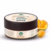 O produto apresentado é um pote de manteiga de pequi da marca Oleoterapia Brasil. Ao lado do pote, há alguns pequis amarelos, ingrediente principal do produto.