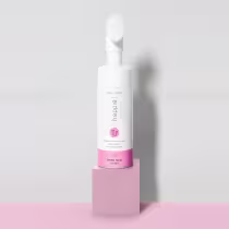 Frasco branco de espuma facial da marca Happie&Co, com rótulo rosa e informações sobre o produto. O frasco possui um aplicador de espuma na parte superior.
