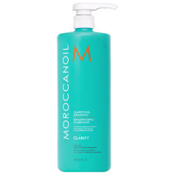 A imagem mostra o Shampoo Purificante Clarify 1L da marca Moroccanoil. Embalagem plástica na cor azul turquesa, com letras brancas e pretas e logotipo da marca em laranja. O frasco tem uma bomba dosadora branca na parte superior.