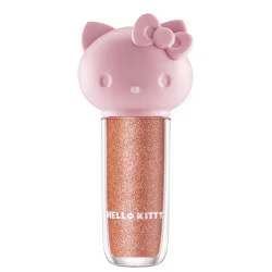 Maquiagem em formato cilíndrico com a cabeça da personagem Hello Kitty como tampa. A parte superior é rosa com detalhes em relevo que representam os olhos, orelhas e laço da Hello Kitty. É possível ver a cor do produto pelo corpo transparente.