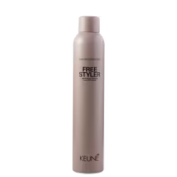 A imagem mostra o spray fixador Keune Free Styler em embalagem cilíndrica de cor bege claro. No frasco está impresso em letras pretas "FREE STYLER 360° freestyling hairspray Laque 360° freestyle". Na parte inferior está escrito "KEUNE" em letras pretas.