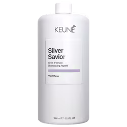 Frasco branco da linha Silver Savior da Keune, contendo shampoo prateado com aroma de flor violeta. Rótulo com nome da marca e produto em destaque.
