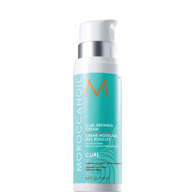 Frasco branco e prata da Moroccanoil contendo creme modelador de cachos, com rótulo azul e laranja indicando "Curl Defining Cream" para todos os tipos de cabelos cacheados.