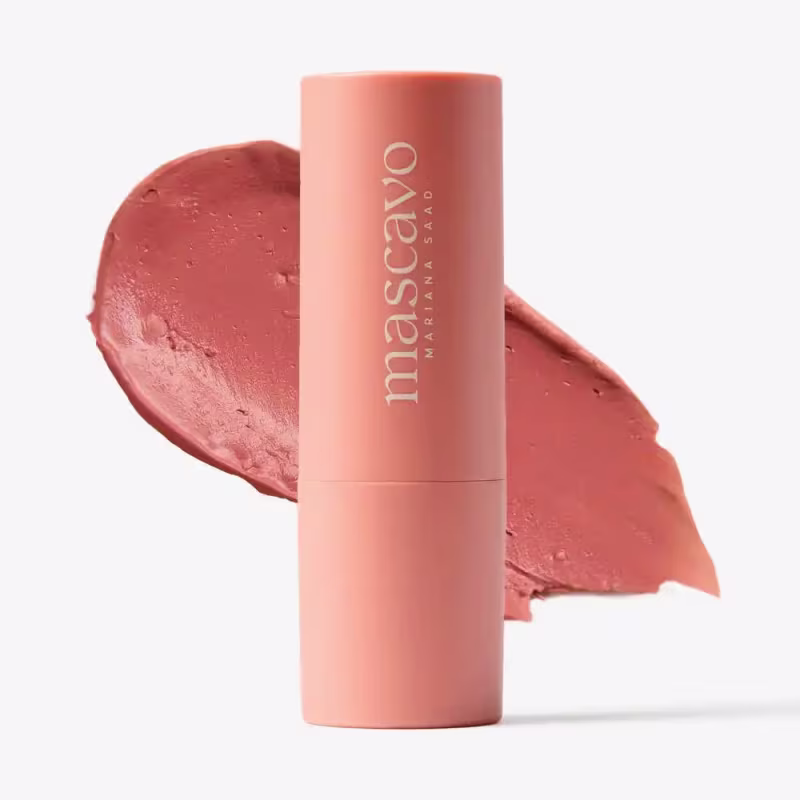 O blush possui uma embalagem cilíndrica de cor rosa clara, com o nome da marca "Mascavo" impresso em branco. O produto parece ter uma textura cremosa e uma cor rosada