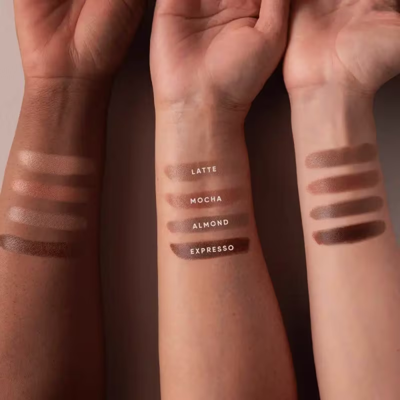 A imagem mostra diferentes amostras de cor do contorno aplicadas em três tons de pele, com os nomes "Latte", "Mocha", "Almond" e "Expresso" escritos abaixo de cada amostra.