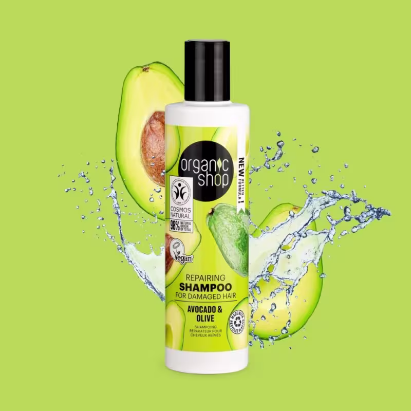 A imagem mostra o shampoo e ao redor dele um abacate partido ao meio partículas de água.