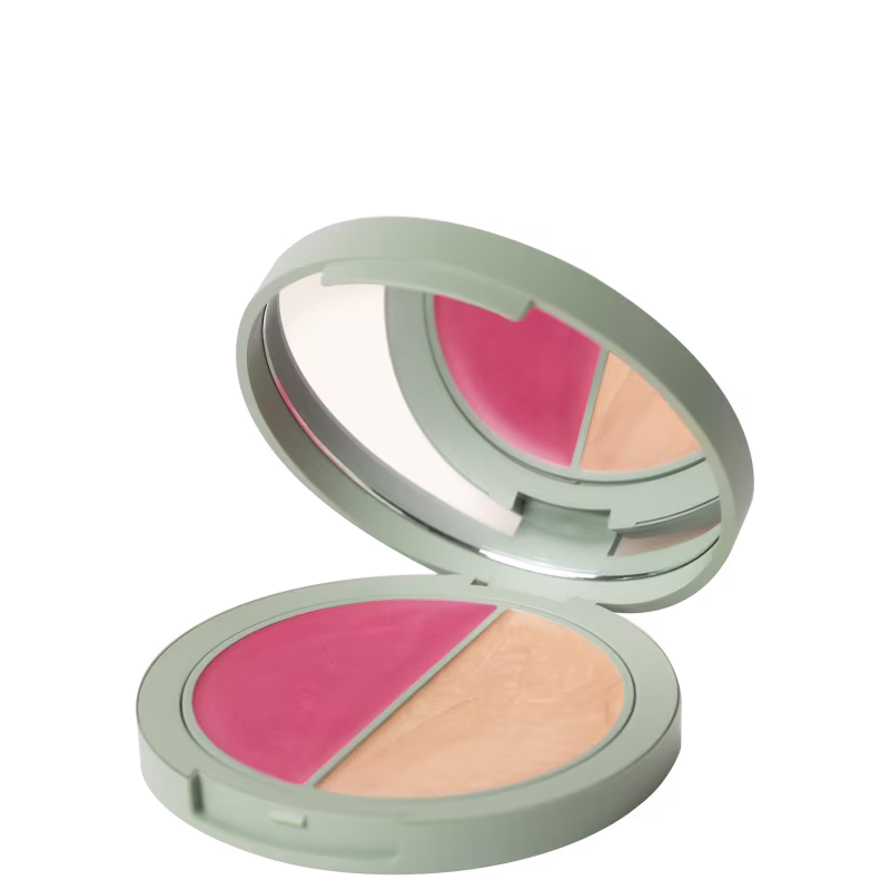 A imagem mostra um paleta em formato arredondado. Ela possui um tom cinza e um espelho circular na parte de cima. Dentro possuem duas cores uma em tom rosa e outro bege.