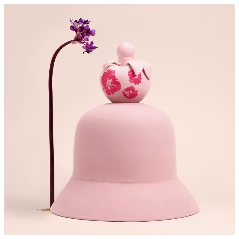 Conjunto de produtos Nina Ricci Nina Fleur. Frasco de perfume transparente em formato de coração com detalhes florais vermelhos. Loção corporal branca em tubo cilíndrico com o nome "Nina Fleur" impresso.