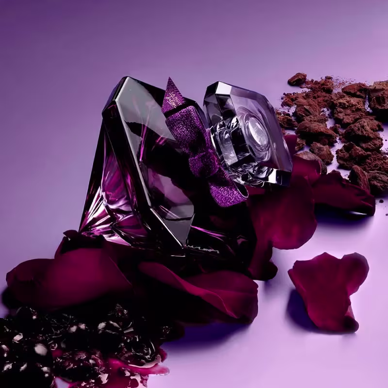 Dois frascos de perfume Lancôme em tons de roxo e cristal. Um frasco tem uma forma facetada e uma tampa com detalhes em malha metálica roxa. O outro frasco é cilíndrico com uma tampa arredondada.
