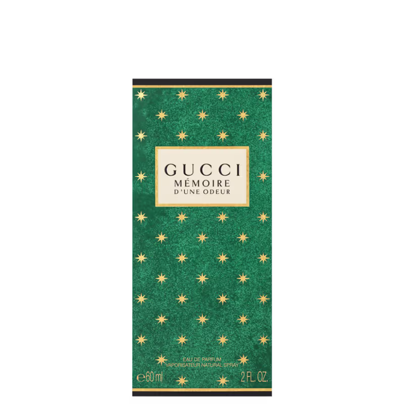 A imagem mostra uma caixa retangular em um fundo branco. A caixa é de cor verde com pequenas estrelas amarelas. Mais acima, uma etiqueta bege com o nome da marca e perfume e, no rodapé, informações de tipo de concentração e volumetria.