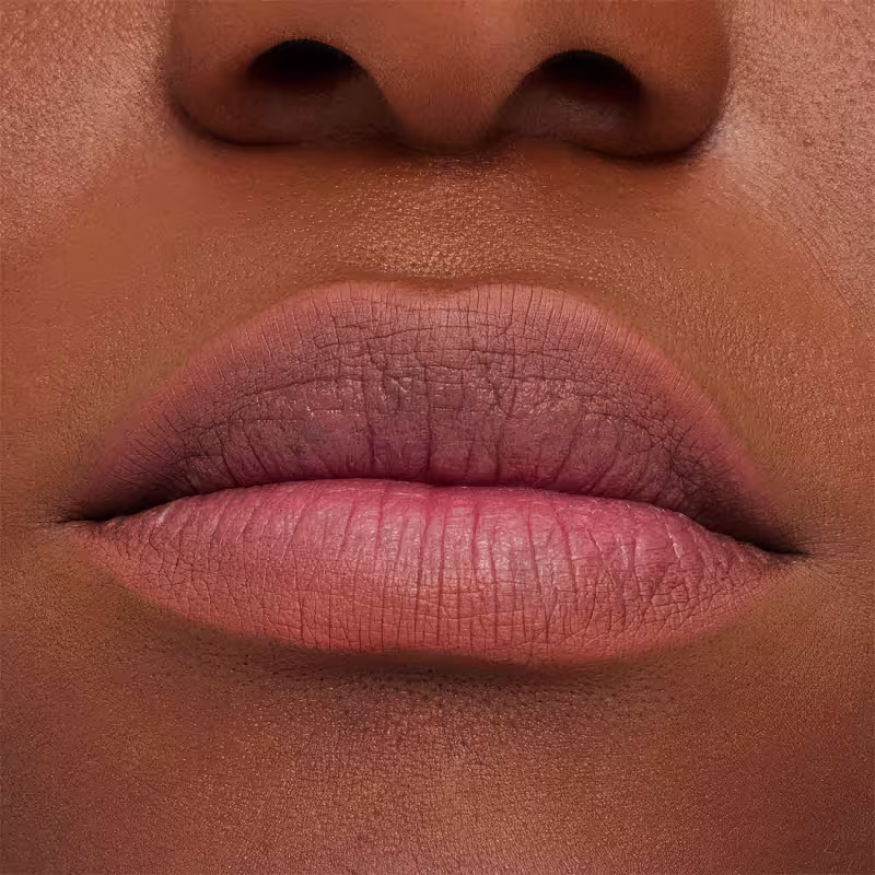 A imagem mostra a boca de uma mulher usando o lápis de boca.