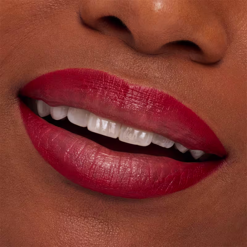 A imagem mostra a boca de uma mulher usando o lápis de boca.