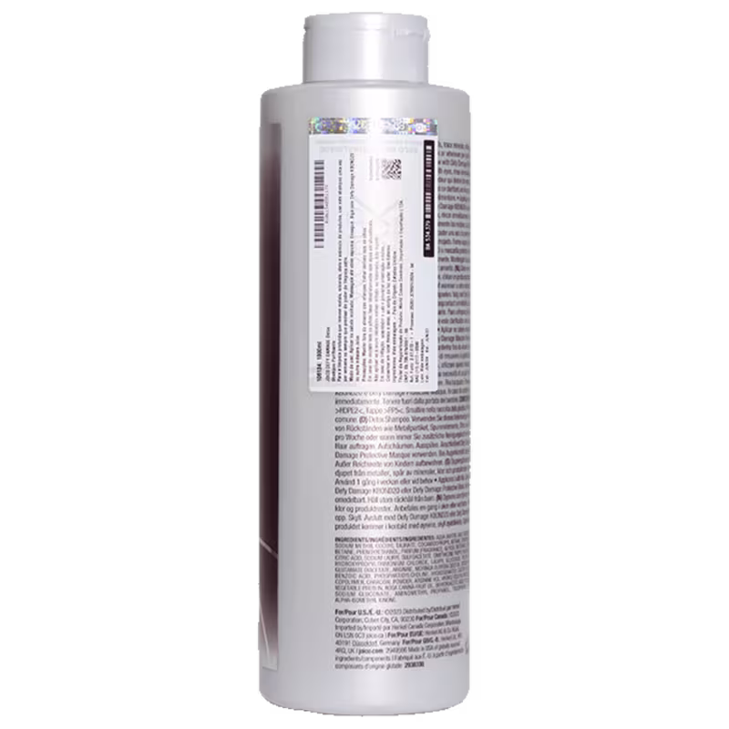 Frasco cilíndrico branco de plástico para shampoo da marca Joico. O rótulo contém informações detalhadas sobre o produto, incluindo ingredientes e instruções, em várias línguas. O frasco tem tampa prata e apresenta as cores branca e roxa.