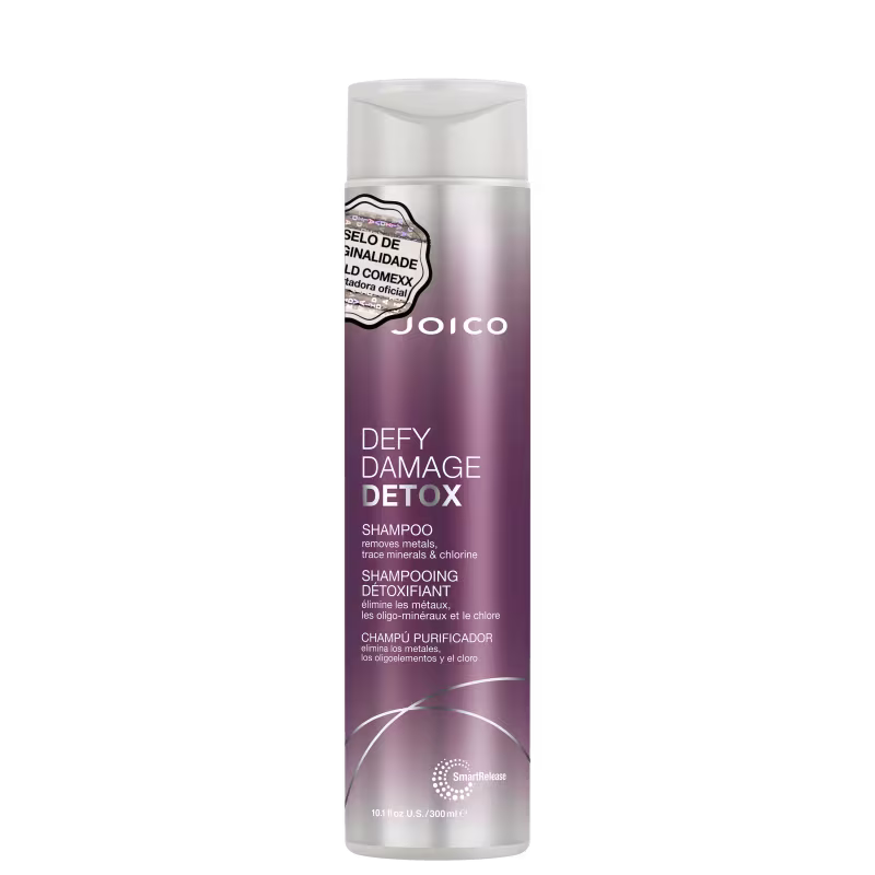 Shampoo detox Defy Damage da marca Joico. Embalagem cilíndrica roxa com detalhes prateados. Rótulo indicando que remove metais, minerais traço e cloro dos cabelos. Volume de 10.1 fl oz / 300ml.