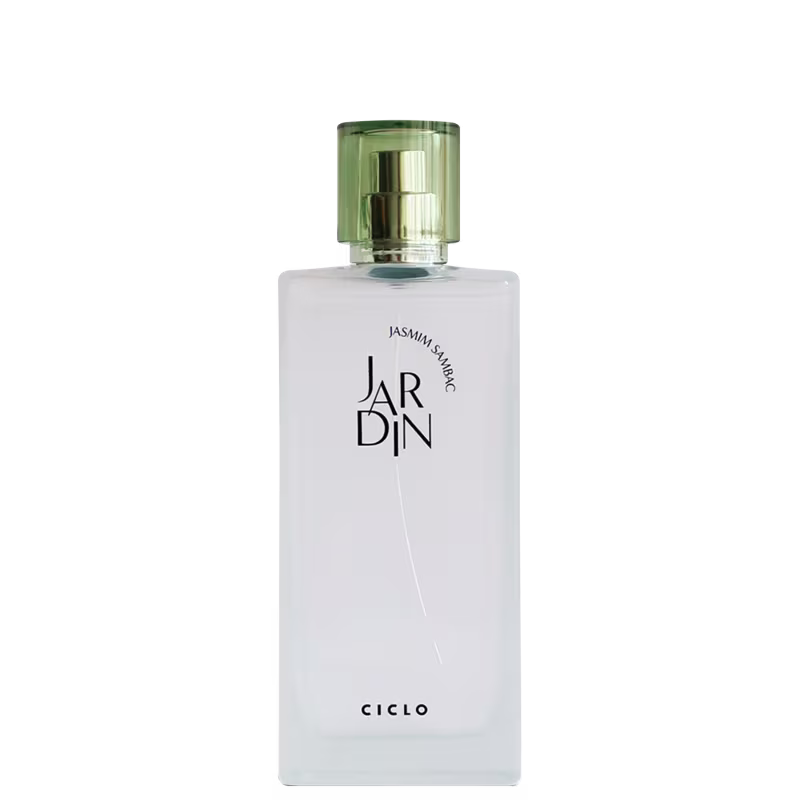 Perfume em frasco retangular de vidro transparente e opaco. A embalagem apresenta o nome "JARDIN" em letras maiúsculas pretas e "Jardim Sambac em letras menores abaixo. Na parte inferior, está escrito "CICLO" em letras maiúsculas pretas.