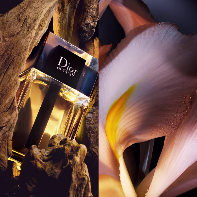 O frasco repousa sobre uma superfície rochosa e áspera. A imagem ao lado mostra uma flor branca com detalhes amarelos no centro.