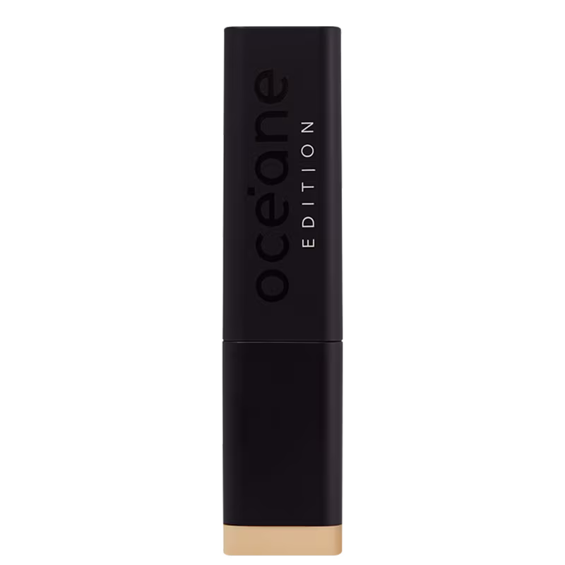 A imagem mostra a embalagem da Base Océane Edition Foundation Stick com formato retangular e cor preta fosca. Destaca a palavra "Océane" em letras maiúsculas pretas e a inscrição "EDITION" abaixo em branco, ambos em relevo na superfície da embalagem.