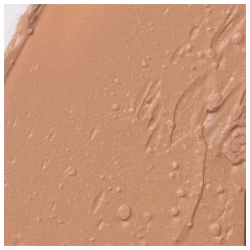 A imagem apresenta detalha da textura da base Océane Edition Foundation Stick. A superfície apresenta uma tonalidade bege escuro e textura em bastão cremosa.