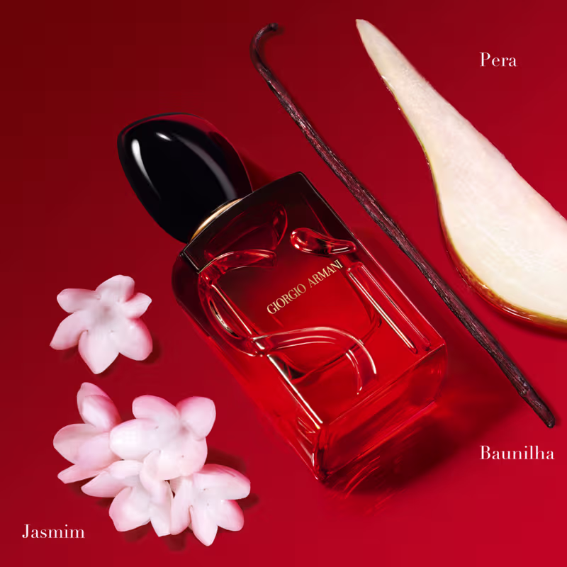 Ao lado do frasco, há alguns elementos decorativos, como flores de jasmin e um bastão de baunilha e uma fatia de pera, que fazem parte da composição olfativa do perfume.